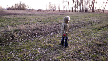 girl in the hood alone, in the background a haystack and a tree. March, spring