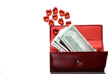 A red wallet is isolated on a white background, from which several banknotes of American 100 dollars are visible, as well as many red hearts, as a symbol of love for money.