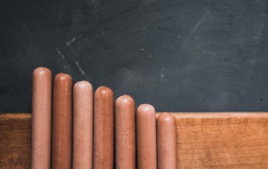 Sausages on a beautiful background for advertising on a wooden board. grey matte concrete background. 