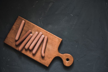Sausages on a beautiful background for advertising on a wooden board. grey matte concrete background. 