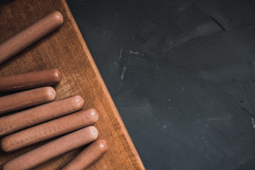 Sausages on a beautiful background for advertising on a wooden board. grey matte concrete background. 