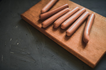 Sausages on a beautiful background for advertising on a wooden board. grey matte concrete background. 