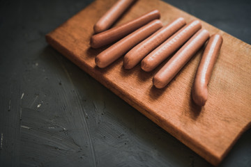 Sausages on a beautiful background for advertising on a wooden board. grey matte concrete background. 