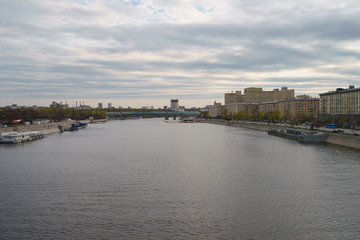 Fototapeta na wymiar Moscow cityscape in in day. Wide Moskva River. Closed public Groky Park on left, Frunzenskaya embankment on right. Academy of Sciences, Andreevsky /Pushkinsky pedestrian bridge, Ministry of Defence