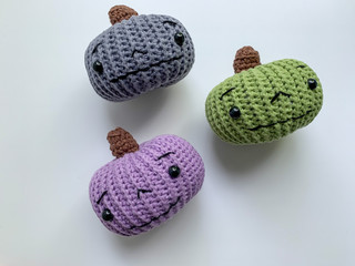 Cute pumpkins of different colors, crocheted on a white background. Handmade for autumn decoration. The day of Halloween and Thanksgiving