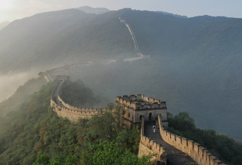 Great wall of China at sunny day. Amazing view of Great Wall at good weather. Mountain view in China with fog. Ancient historical wall near the beautiful landscape. Chinese people. Tourism in China.