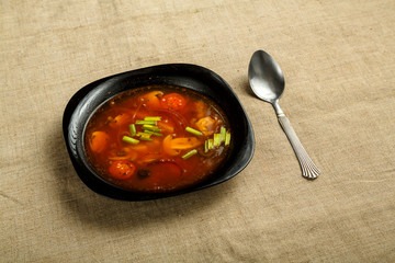 black plate of italian tomato soup with potatoes and mushrooms.