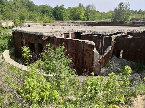 Old Soviet bunker, bomb shelter. Rusty metal walls. Concrete plates. Around green plants and trees