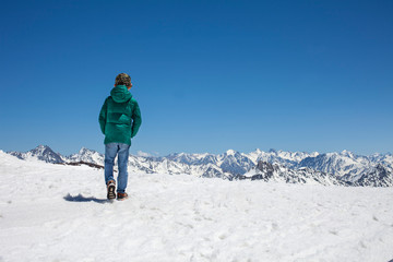 Fototapeta na wymiar Boy walks in snowy mountatins with clear sky
