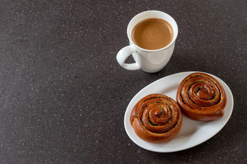 Buns with poppy seeds and a cup of coffee. Korvapuusti are Finnish cinnamon buns. Copy space. 	