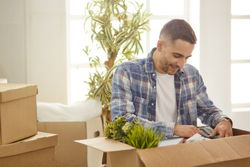 Handsome man with boxes in the new apartment after moving