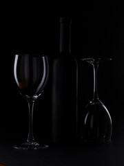 Wine glasses on black backround and wine bottles