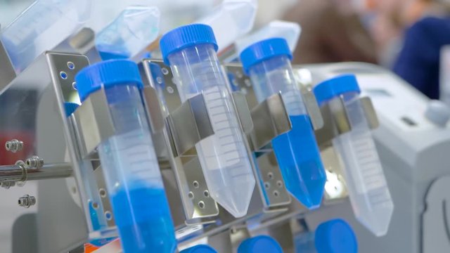 Digital tube rotisserie rotator for effective mixing biological samples at pharmacy factory, medical exhibition: close up, slow motion. Chemistry, pharmaceutical, laboratory equipment concept
