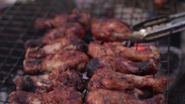 Close-up of woman hand flipping meat with serving tongs on metal grate at beach - Luang Phabang, Laos