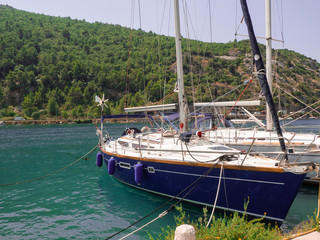 Barco velero en las aguas verdes de Croacia, con las montañas llenas de árboles verdes al fondo. Verano de 2019