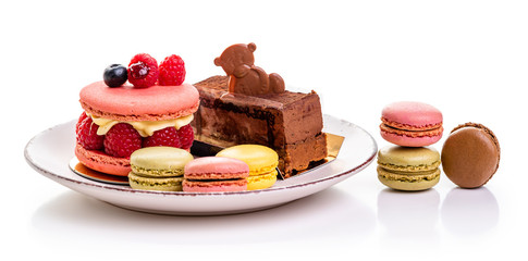 italian Raspberry macaron. Brownies with raspberries and cream, chocolate cake with a chocolate bear and multi-colored macarons on a plate 