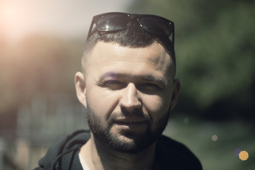 Portrait of handsome man with beard and sunglasses. Close-up photo in the park.