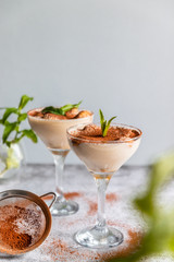 Tasty Italian tiramisu decorated with mint in a glass on a grey background. Copy space. Vertical photo