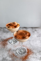 Close up of a traditional Italian sweet tiramisu cake dessert in glass on grey background. Copy space.