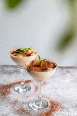 Close up of a traditional Italian sweet tiramisu cake dessert in glass on grey background. Copy space. Vertical photo