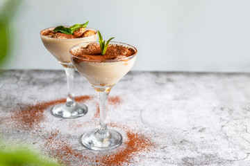 Close up of a traditional Italian sweet tiramisu cake dessert in glass on grey background. Copy space. Menu, recipe