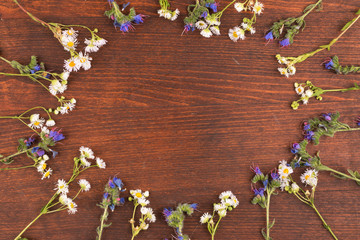 Frame of wildflowers lying on a wooden surface. Copy space.