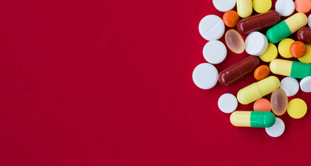 Medical background with pills and capsule on red background.Assorted pharmaceutical medicine pills, tablet. Heap of various assorted medicine tablets and pills different colors. Health care. Top view