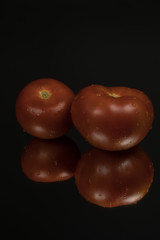 Tomato on black reflective studio background. Isolated black shiny mirror background for every concept.