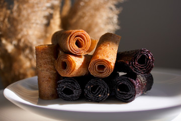 Fruit leather of apples and berries in rolls (Russian pastila). Background for text and articles on healthy eating. Raw food, vegan sweetness, dessert without sugar and flour.