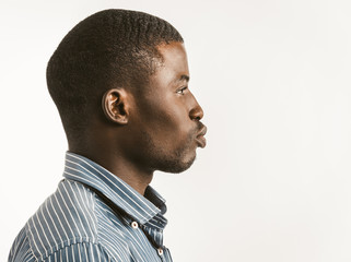 African-American black businessman in a shirt looks to the side with lips extended as for a kiss. Cut out on white background with copy space at right side. Toned image