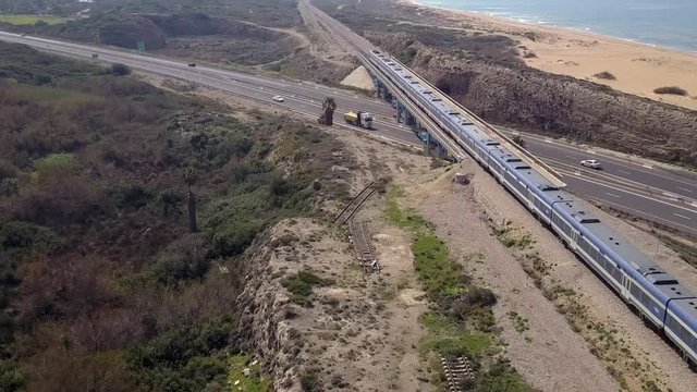 Passenger Train crossing a highway bridge with traffic passing below, Top down aerial view.