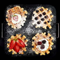 Viennese waffles with strawberries, black currants, blackberries, topped with chocolate, whipped cream and powdered sugar.