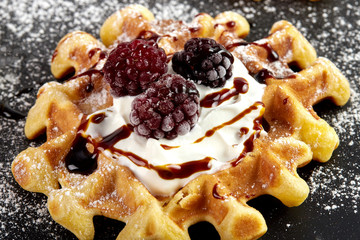 Viennese waffles with strawberries, black currants, blackberries, topped with chocolate, whipped cream and powdered sugar.