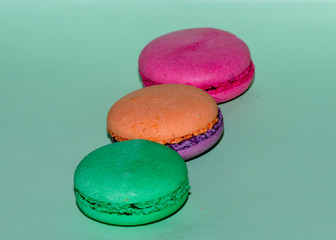 Delicious three multicolored macaroon on a green background