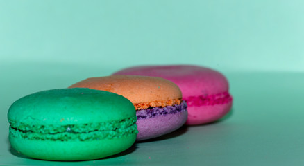 Delicious three multicolored macaroon on a green background