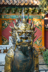 Chinese bronze dragon on the background of the colorful temple wall.