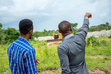 two african men, surveying a piece of land