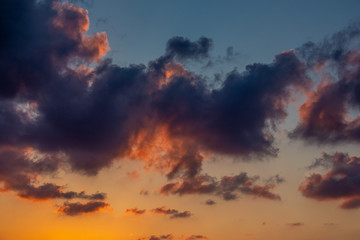 Beautiful sky and clouds are lit by the setting sun. Orange sunset, blue sky.