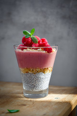 Fresh healthy dessert of Chia seeds raspberry puree banana and muesli in a glass