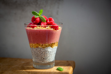 Fresh healthy dessert of Chia seeds raspberry puree banana and muesli in a glass