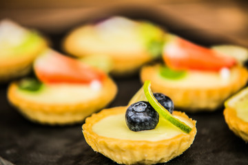 Sweet dessert Tartlets with fresh blueberry and delicious cream. Closeup