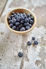 Image of blueberries in wooden bowl on rustic village table.