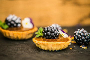 Sweet dessert Tartlets with fresh blackberry and delicious cream. Closeup