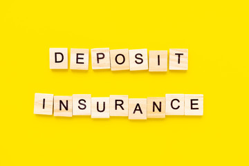 words deposit insurance. Wooden blocks with lettering on top of yellow background. insurance concepts.