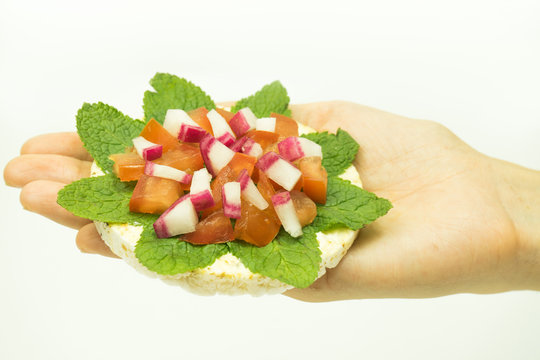 Beautiful rice cake sandwich with tomatoes and radish in the hand on white bacjground.Fit healthy vegetarian snack close up .Organic food concept.