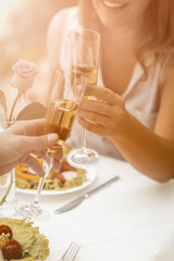 Happy couple drink white wine at seaside cafe outdoors. Man and woman have romantic date on the sandy beach. Close up shot. Toned image