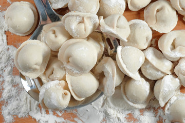 Raw dumplings on a wooden board. Traditional homemade food. The process of making dumplings. Top view