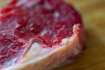 Shots of a sliced raw  fresh rump steak with fat on the steak on a wooden board