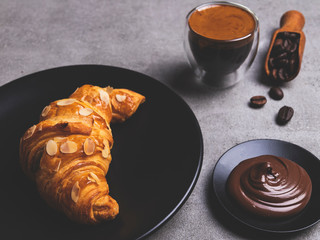 Yummy fresh croissant sliced almonds with coffee and chocolate paste on plate