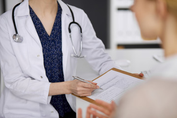 Doctor and patient discussing current health examination while sitting in clinic. Perfect medical...